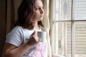 Woman by a window in soft morning light, contemplating methylated B-vitamins and anxiety