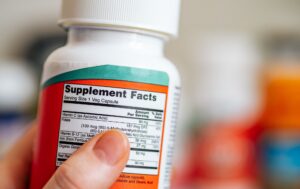 Person reading the label on a methylated B-vitamin supplement bottle