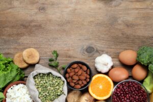 Whole foods rich in B-vitamins including eggs, leafy greens, and seeds arranged on a wooden surface — natural sources of B12, folate, and other B-vitamins important after age 40.