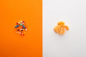 Orange slices arranged next to vitamin pills, illustrating the natural vs synthetic vitamins comparison that dominates supplement marketing.