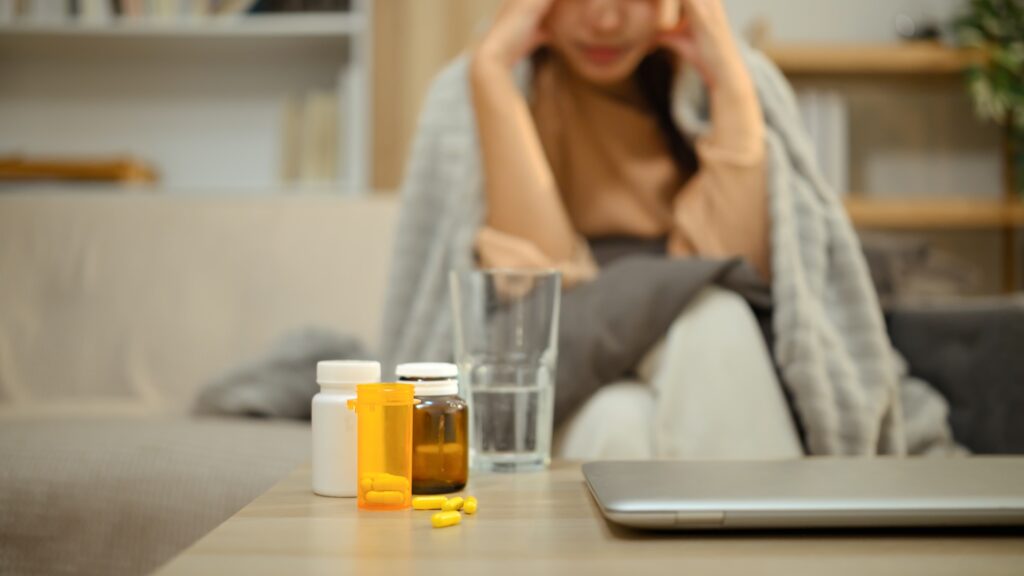 Woman experiencing anxiety and panic at a table with methylated B-vitamin supplements — a common reaction for methyl-sensitive adults