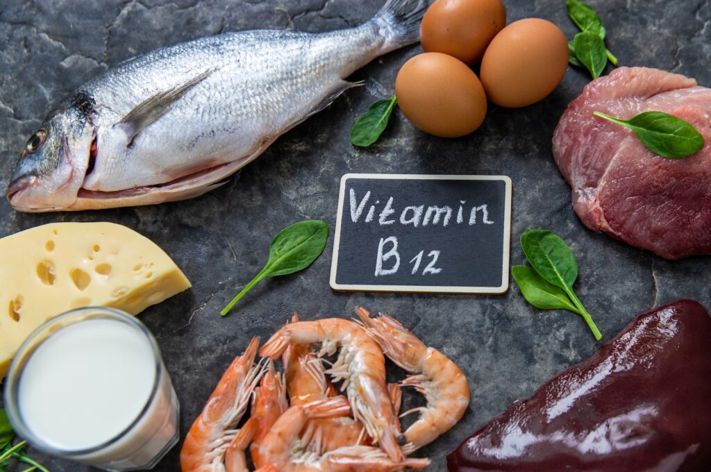 Vitamin B12 rich foods including meat, fish, eggs, dairy, and shellfish arranged around a B12 label