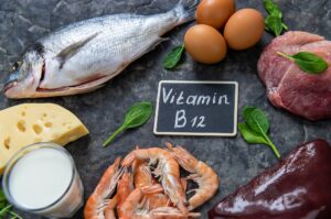 Vitamin B12 rich foods including meat, fish, eggs, dairy, and shellfish arranged around a B12 label