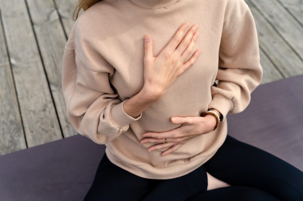 Woman holding one hand on her stomach and one hand on her heart, illustrating the gut-brain connection at the root of anxiety.