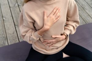 Woman holding one hand on her stomach and one hand on her heart, illustrating the gut-brain connection at the root of anxiety.